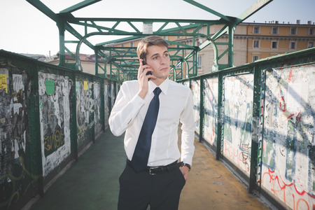 young handsome elegant blonde model man using smartphone in the city