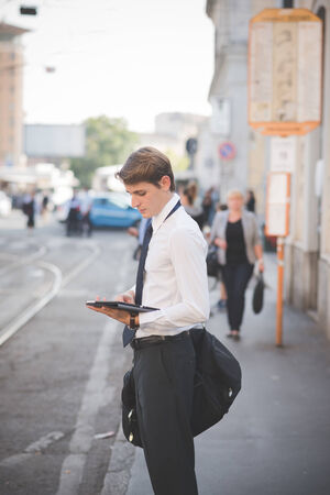 young handsome elegant blonde model man using tablet technological device in the cityの写真素材