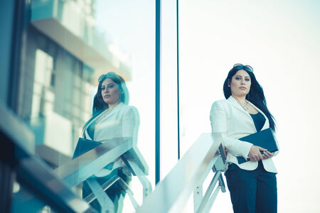 beautiful long black hair elegant business woman with tablet  in the cityの写真素材