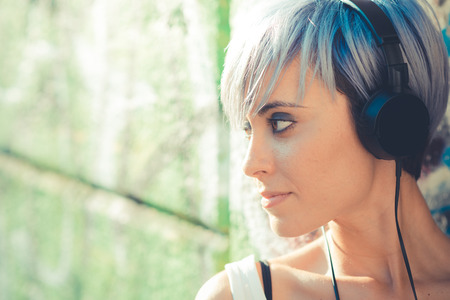 young beautiful short blue hair hipster woman with headphones music in the city