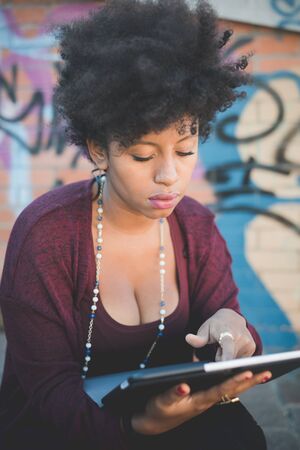 beautiful black curly hair african woman using tablet in townの写真素材