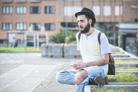 young handsome hipster gay modern man using smartphone in townの写真素材