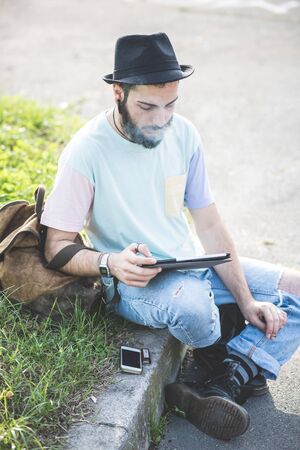 young handsome hipster gay modern man using tablet in townの写真素材