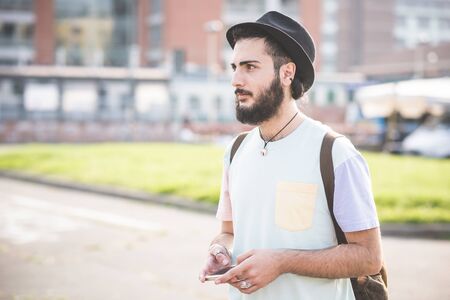 young handsome hipster gay modern man using smartphone in townの写真素材
