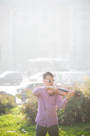 young crazy funny musician violinist asian man in town outdoor lifestyleの写真素材