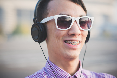 young crazy funny asian man in town outdoor lifestyle listening music with headphones and tabletの写真素材