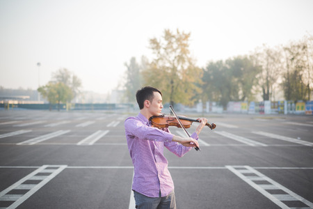 young crazy funny musician violinist asian man in town outdoor lifestyleの写真素材