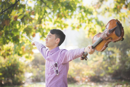 young crazy funny musician violinist asian man in town outdoor lifestyleの写真素材