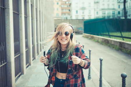 beautiful young blonde hair woman hipster listening music in the cityの写真素材