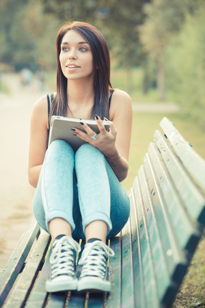 young beautiful brunette straight hair woman using tablet outdoorの写真素材