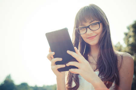 beautiful young woman with white dress using tablet in the cityの写真素材
