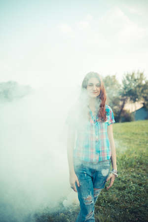 beautiful young hipster woman smoke fog in the parkの写真素材