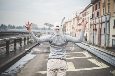 surreal woman with a rabbit mask - conceptual shot in urban landscape