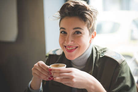 young beautiful short hair hipster woman at the bar drinking coffee