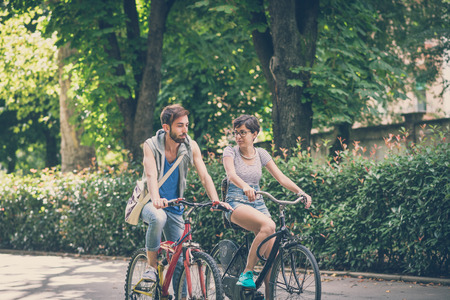 couple of friends young  man and woman riding bike in the city