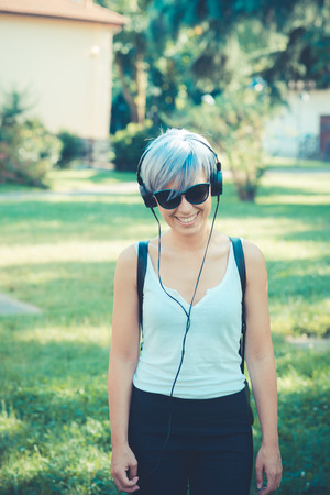 young beautiful short blue hair hipster woman with headphones music in the cityの写真素材