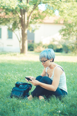 young beautiful short blue hair hipster woman using tablet device in the cityの写真素材