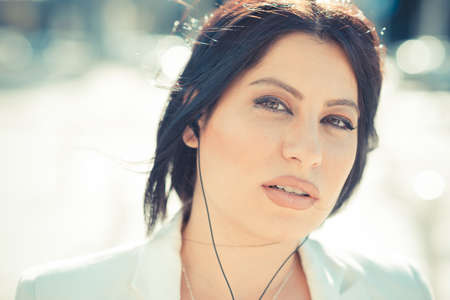 beautiful long black hair elegant business woman with earphones in the cityの写真素材