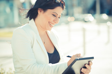 beautiful long black hair elegant business woman using tablet in the cityの写真素材