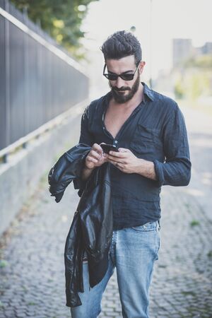young handsome attractive bearded model man using smartphone in urban contextの写真素材
