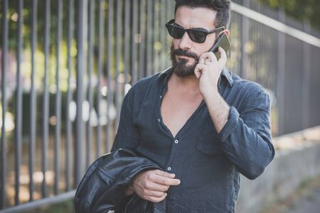 young handsome attractive bearded model man using smartphone in urban contextの写真素材
