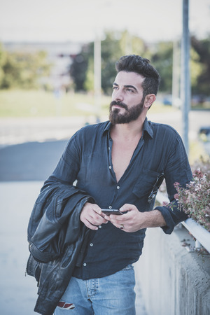 young handsome attractive bearded model man using smartphone in urban contextの写真素材