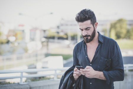 young handsome attractive bearded model man using smartphone in urban contextの写真素材