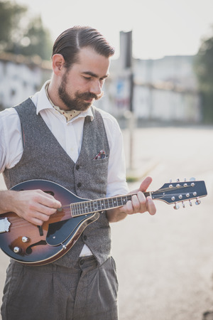 handsome big moustache hipster man playing mandolin in the cityの写真素材