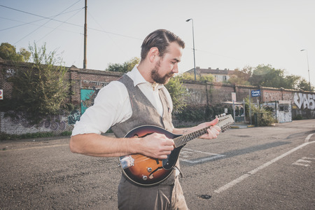 handsome big moustache hipster man playing mandolin in the cityの写真素材