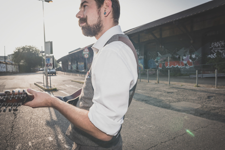 handsome big moustache hipster man playing mandolin in the cityの写真素材