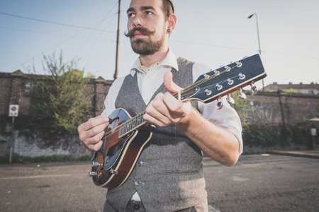 handsome big moustache hipster man playing mandolin in the cityの写真素材