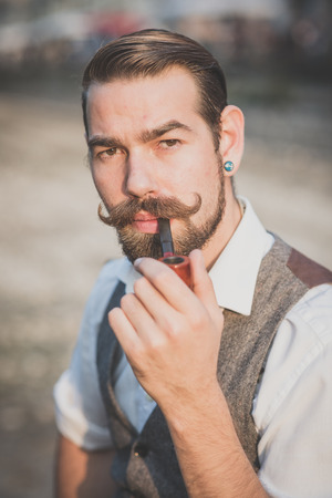 handsome big moustache hipster man smoking pipe  in the cityの写真素材