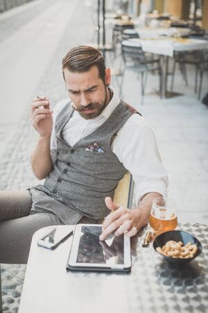 handsome big moustache hipster man using tablet sitting at the barの写真素材