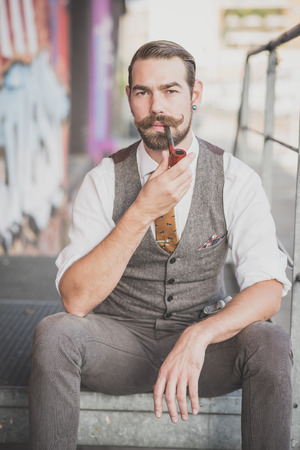 handsome big moustache hipster man smoking pipe in the cityの写真素材