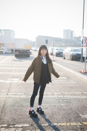 young beautiful asian hipster woman in the city - living town during sunset in backlitの写真素材