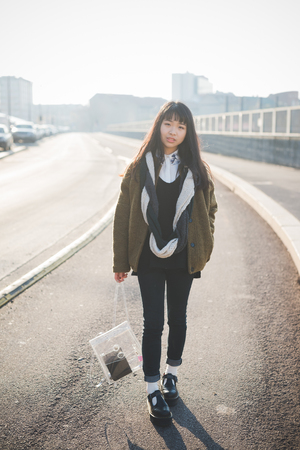 young beautiful asian hipster woman in the city - living town during sunset in backlitの写真素材