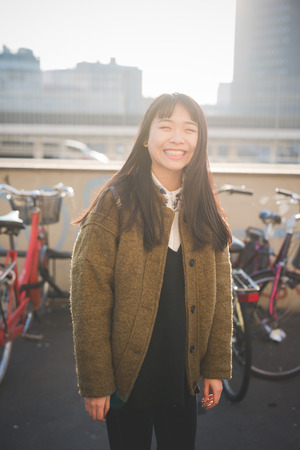 young beautiful asian hipster woman in the city - living town during sunset in backlitの写真素材