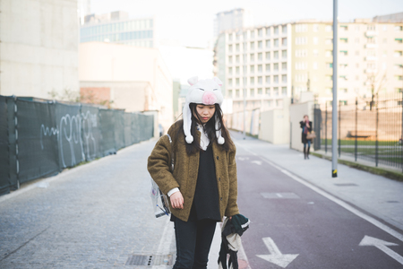 young beautiful asian hipster woman in the city - wearing funny piggy winter capの写真素材