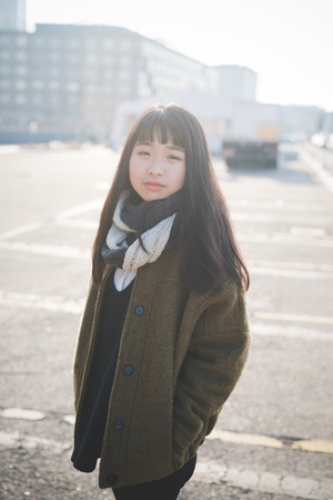 young beautiful asian hipster woman in the city - living town during sunset in backlitの写真素材