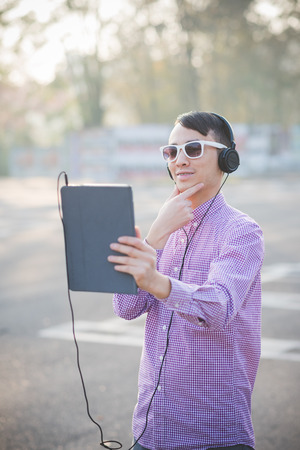 young crazy funny asian man in town outdoor lifestyle listening music with headphones and tabletの写真素材
