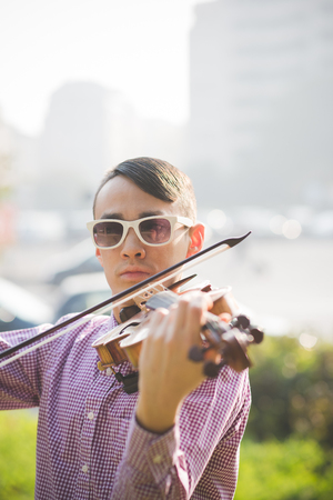 young crazy funny musician violinist asian man in town outdoor lifestyleの写真素材