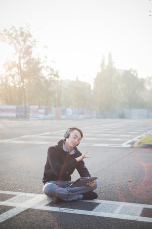 young crazy funny asian man in town outdoor lifestyle listening music with headphones and tabletの写真素材