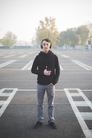 young crazy funny asian man in town outdoor lifestyle listening music with headphonesの写真素材