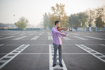 young crazy funny musician violinist asian man in town outdoor lifestyleの写真素材