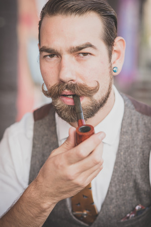 handsome big moustache hipster man smoking pipe in the cityの写真素材