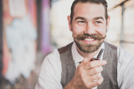 handsome big moustache hipster man smoking pipe in the cityの写真素材
