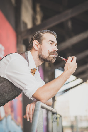 handsome big moustache hipster man smoking pipe in the cityの写真素材