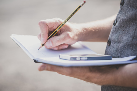 close up hands man writing on diary and smartphone outdoorの写真素材