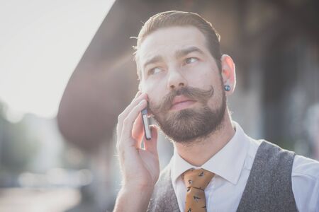 handsome big moustache hipster man calling with cellphone in the cityの写真素材