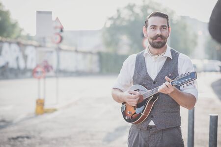 handsome big moustache hipster man playing mandolin in the cityの写真素材